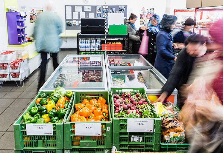 Sozialmarkt - Innenaufnahme SOMA mit Gemüse, Obst und Kühltruhen, viele Menschen beim EInkauf
