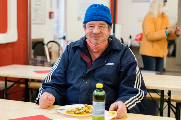Älterer Mann mit Haube genießt seine warme Mahlzeit vom Samariter Suppentopf