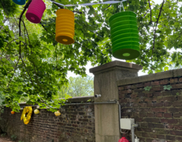 Eine Mauer ist bunt geschmückt. Im Baum hängen Lampions. 