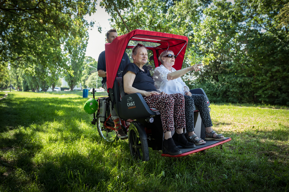 Zwei ältere Frauen sitzen in einem speziellen Fahrzeug und genießen einen Ausblick.