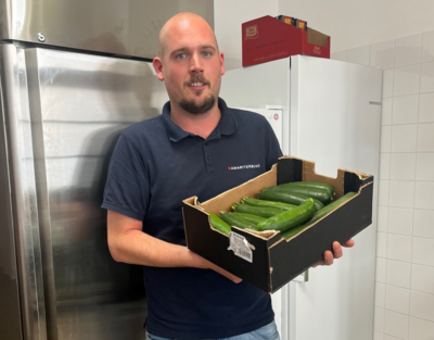Koch vom Samariter Suppentopf hält eine Schachtel mit Zucchinis in der Hand