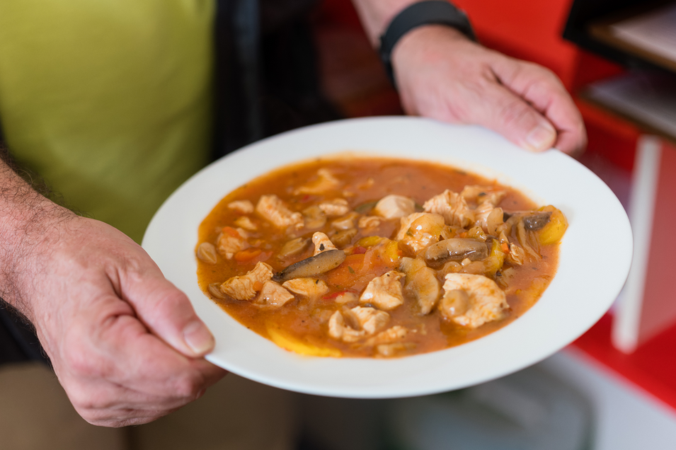 Ein Mann hält einen Teller mit schmackhafter Hühnersuppe und Gemüse.
