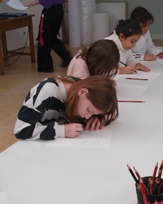 Vier Mädchen zeichnen nebeneinander an einem Tisch.