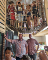 Gruppenbild LernLEO-Kinder in Indoor-Spielraum, Klettermöglichkeiten, Erwachsene davor