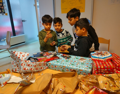 Vier Jungs vom LernLeo packen gerade Geschenke von der LErnLeo Christkindaktion aus.