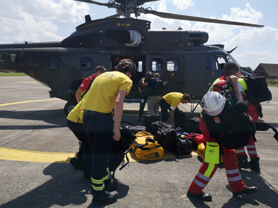 Hilfskräfte mit Gepäck vor Hubschrauber