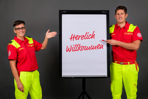 Zwei Trainer:innen vom Samariterbund Wien zeigen auf ein Flipchart auf dem 