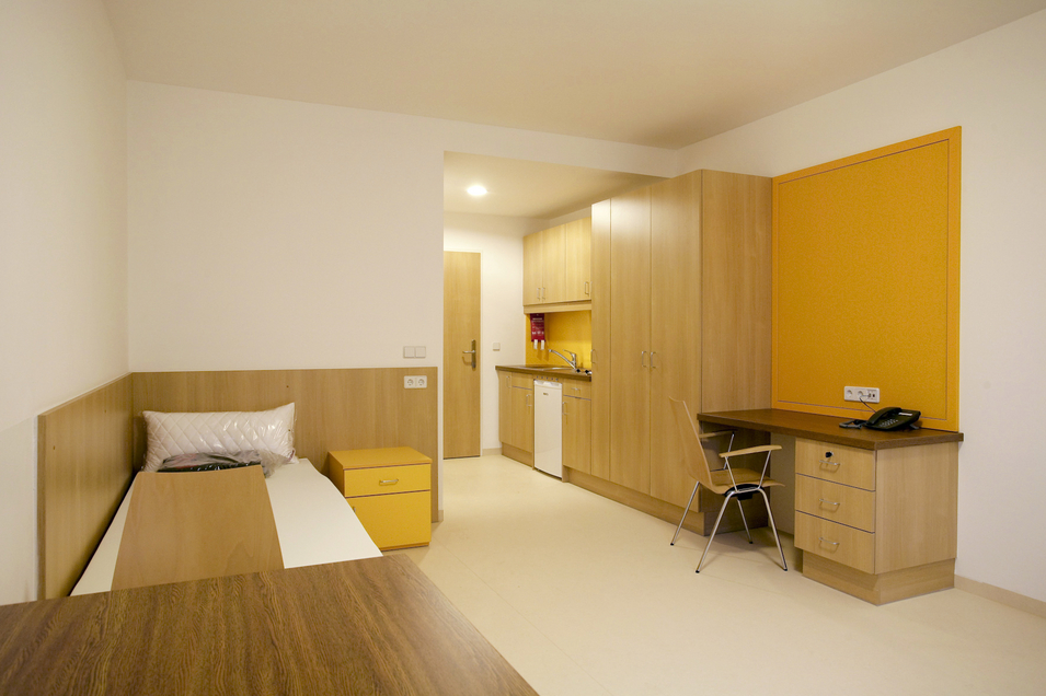 Haus Max Winter - Ansicht Einzelzimmer mit Bett, Küche und Schreibtisch