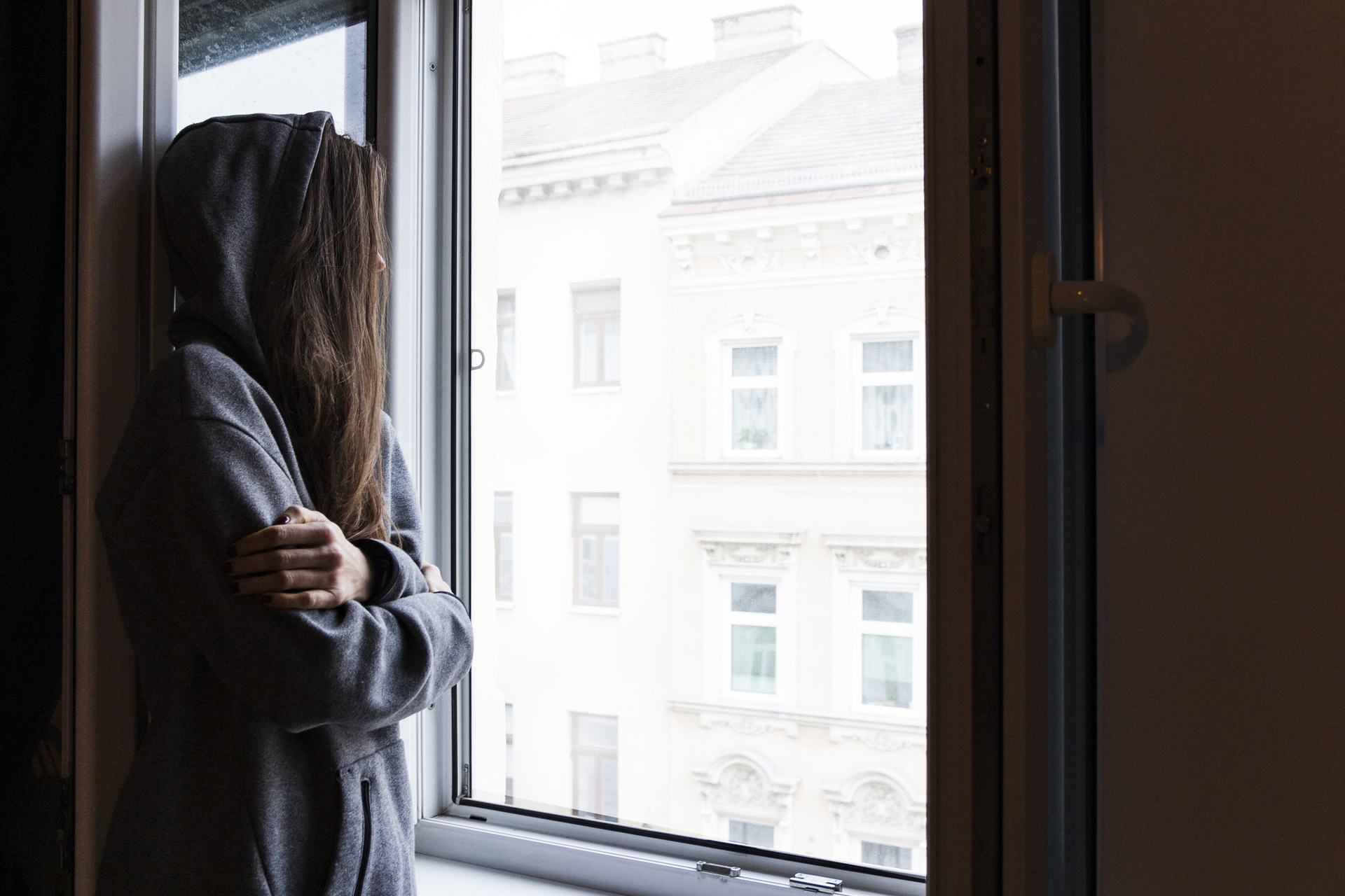 Von der Seite fotografierte Frau sieht durch Fenster