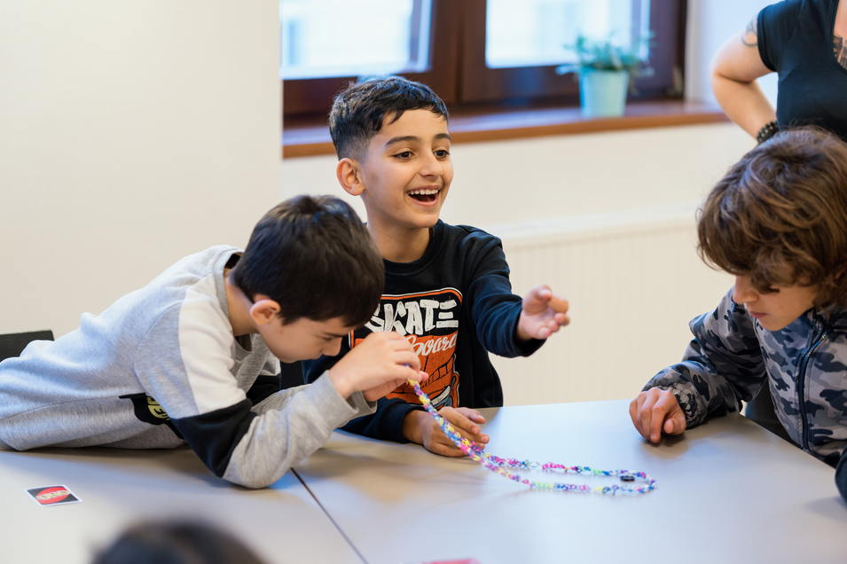 drei Jungs an einem Tisch, spielen mit Karten und lachen