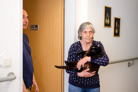 Altere Frau hält ihre schwarze Katze am Arm 