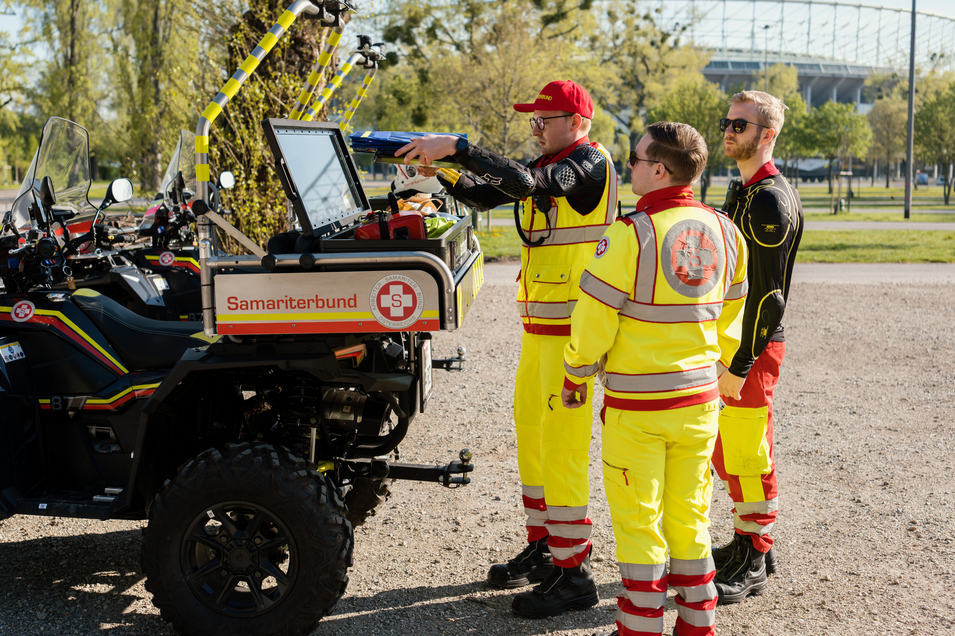 Drei Sanitäter bereiten Quad für Einsatz vor und befüllen es mit Material