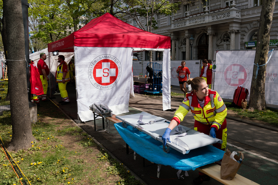 Rettungssanitäterin richtet ihre Station bei einer Veranstaltung ein und steht neben Transportliege