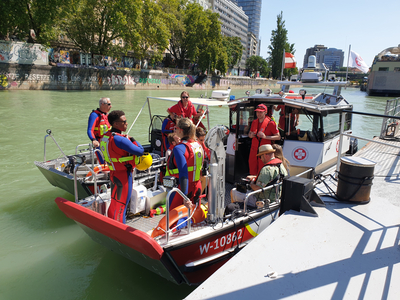mehrere Personen der Wasserrettung in Neopren-Anzügen auf Wasserrettungsboot am Donaukanal in Wien