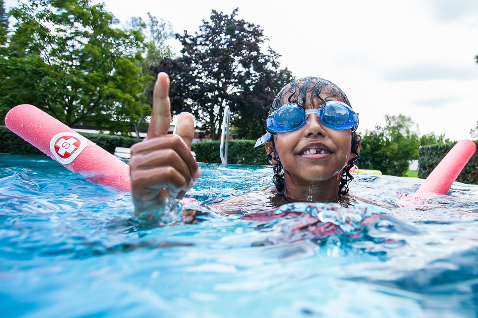 Kind mit Taucherbrille und Poolnudel im Pool
