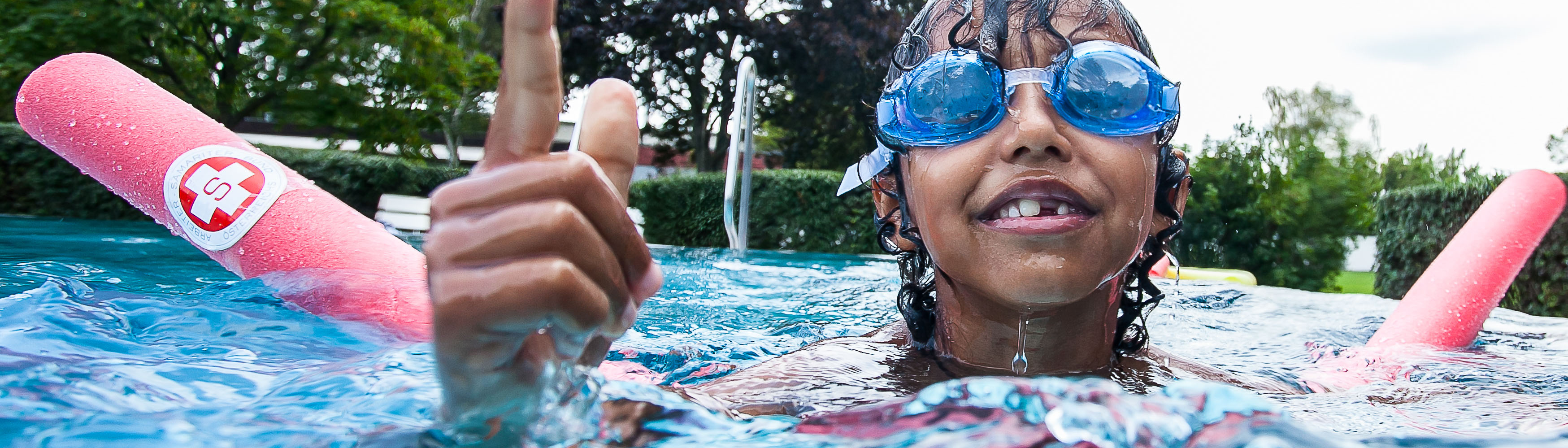 Kind mit Taucherbrille und Schwimmhilfe in Pool
