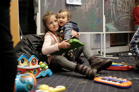 Zwei Schwestern sitzen in Flüchtlingseinrichtung auf Teppichboden und spielen