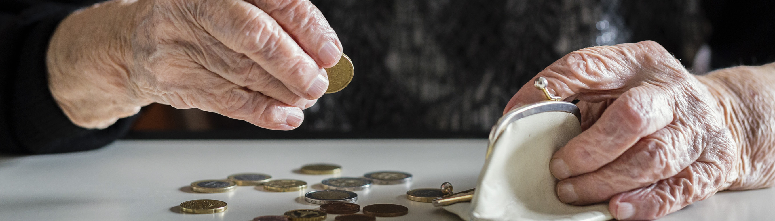 Hände von alter Frau zählen Geld am Küchentisch