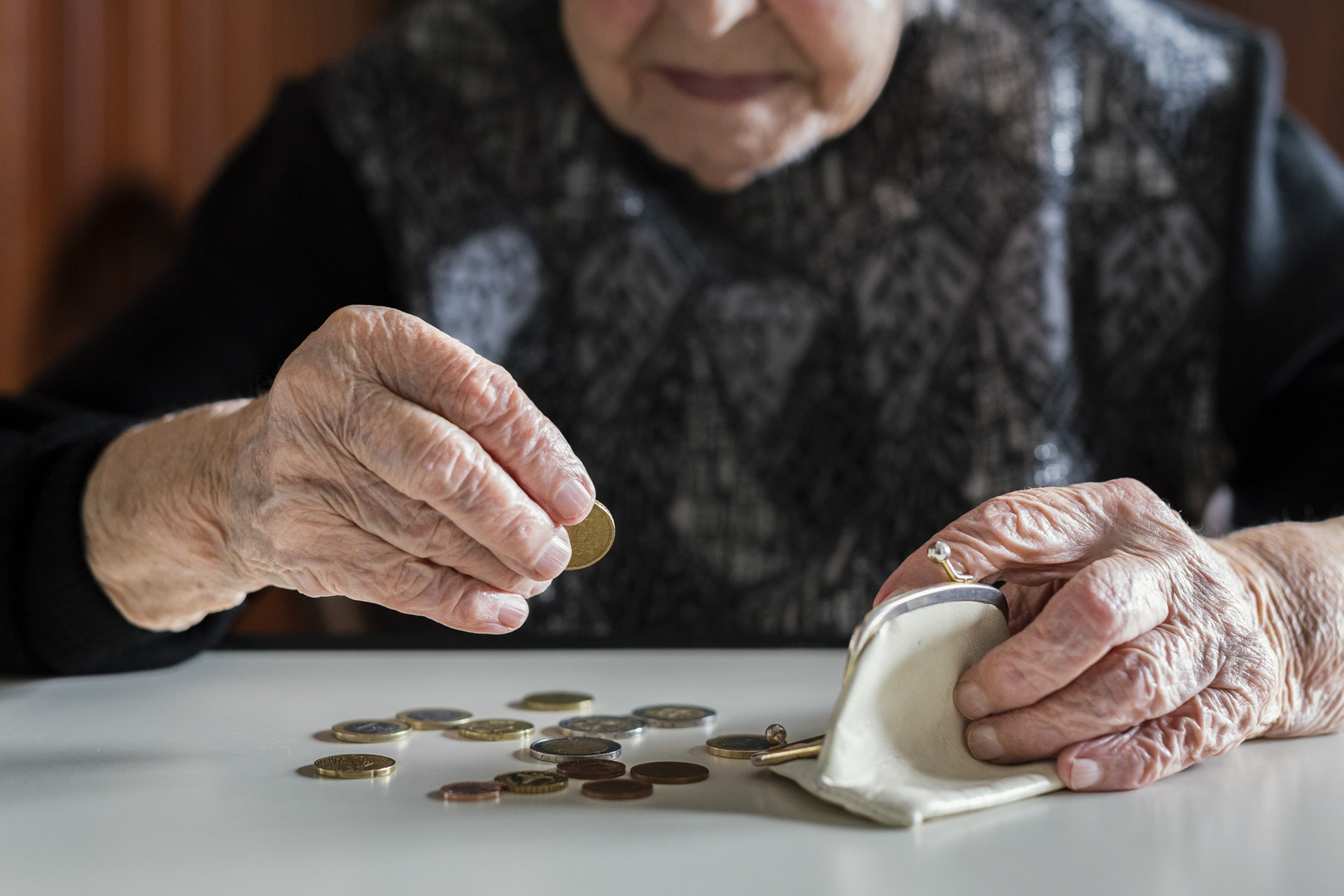 Hände von alter Frau zählen Geld am Küchentisch