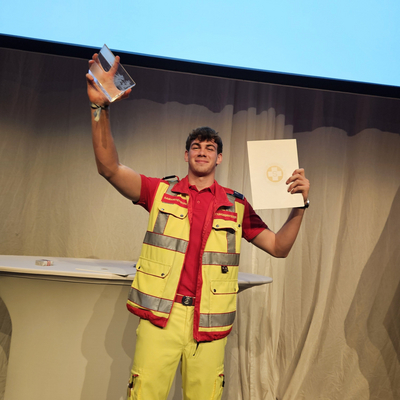 Zivildiener des Jahres bei Preisverleihung mit Urkunde und Pokal in der Hand