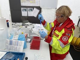 Eine Rettungskraft analysiert Proben an einem medizinischen Arbeitsplatz.