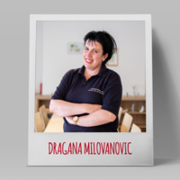 Lächelnde Frau in schwarzem Shirt, steht mit verschränkten Armen.