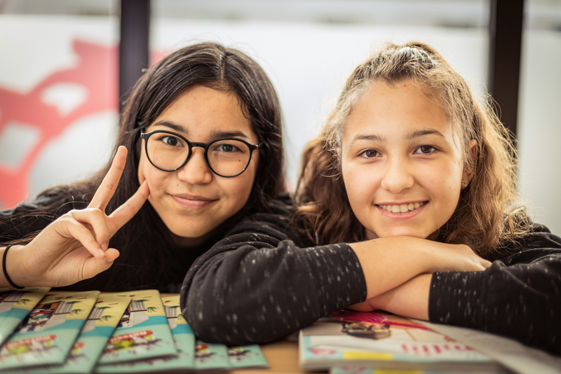 zwei Mädchen aus dem LernLEO stützen sich auf Tisch, Kopf auf Händen abgestützt