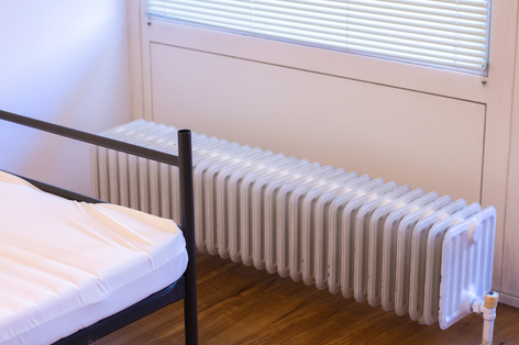 Einzelzimmer einer Eichrichtung mit Bett und Heizkörper