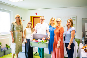 Gruppenbild mit fünf Frauen und einem Mann, der eine Obstkiste hält