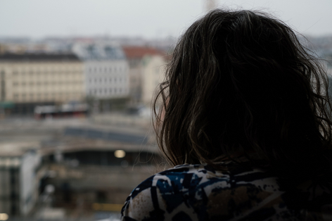 Aufnahme von hinten während Frau aus Fenster blickt