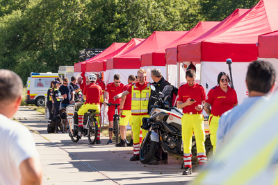 mehrere Personen in Samariterbund Uniformen stehen vor Zelten mit verschiedenen mobilen Einheiten, Stimmungsvolle Aufnahme mit Tiefenschärfe