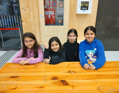 Vier Mädchen sitzen wartend und voller Vorfreude an einem Tisch.