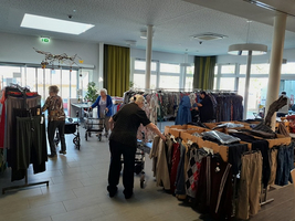 Ältere Frauen stöbern in einem Kleidergeschäft zwischen Regalen mit Kleidung.