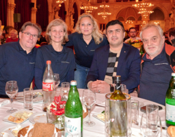 Fünf Personen sitzen in einem Saal vor einem gedeckten Tisch.