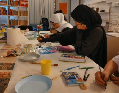 Mädchen sitzen am Tisch, Wasserfarben, Mädchen malt mit einem Pinsel ein Bild