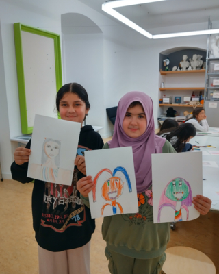 Zwei Mädchen halten drei selbst gemalte Bilder hoch. 