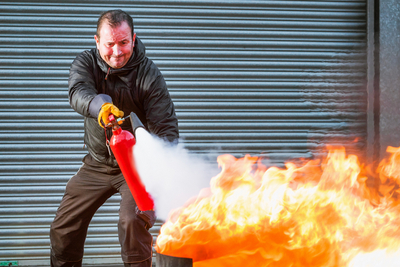 Ein Mann löscht einen Brand mit einem Feuerlöscher