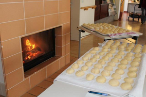 Auf einem Tisch liegen viele Teigbälle, daneben brennt ein Kamin.