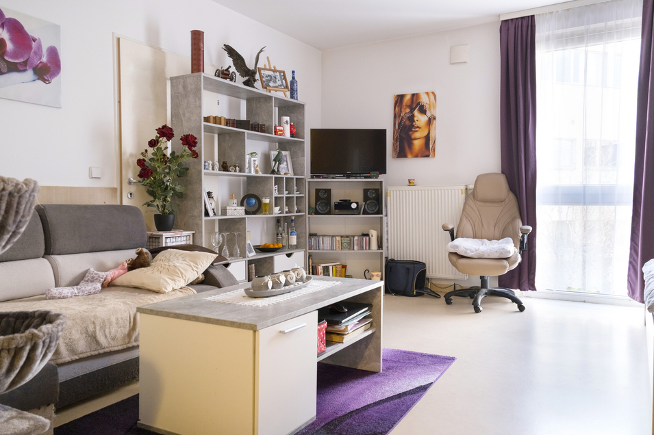 Haus Max Winter - Ansicht bewohntes Einzelzimmer mit Sofa, Regal, Tisch und Fernseher