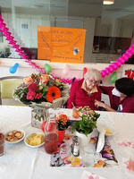 Eine ältere Dame feiert ihren 90. Geburtstag mit Blumen und festlicher Dekoration.