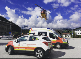 Rettungshubschrauber fliegt über Fahrzeuge des Samariterbundes und der Polizei.