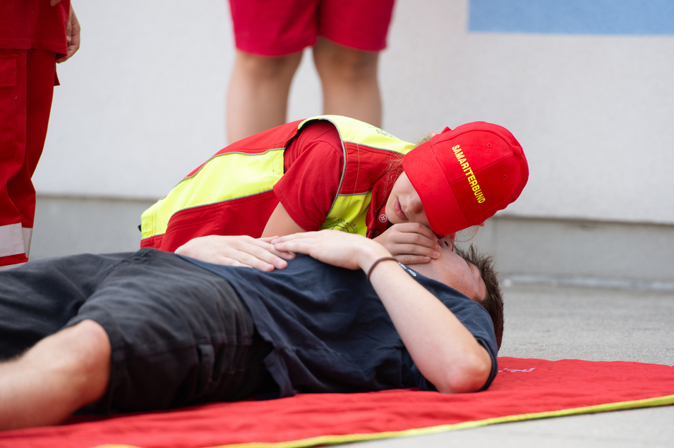 Ein Kind leistet Herz-Lungen-Wiederbelebung an einer liegenden Person.