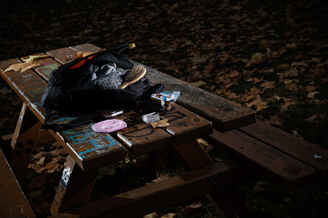 Rucksack auf Tisch in Park mit Zigaretten und Hygieneartikeln