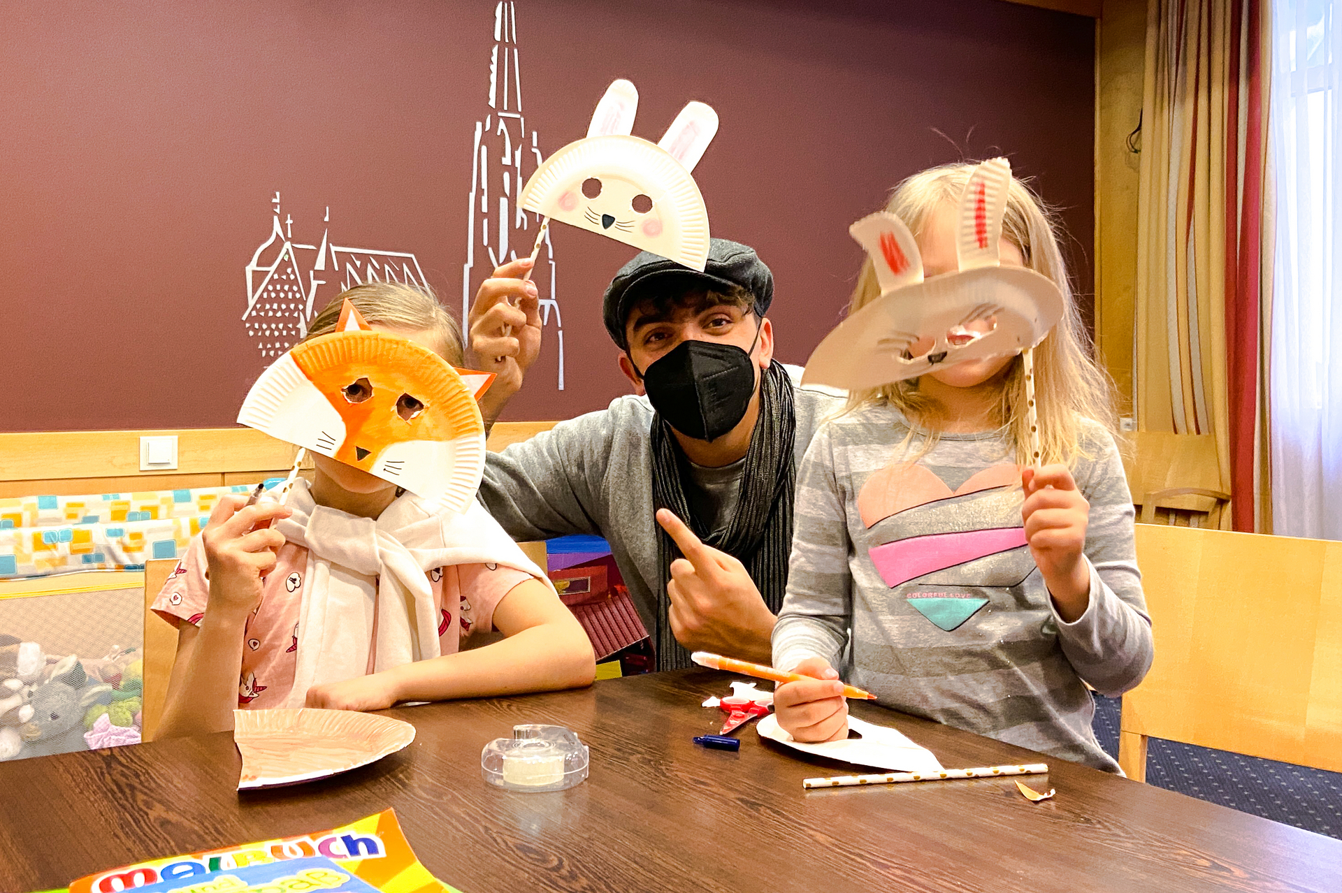Ukraine Soforthilfe – Betreuer mit zwei kleinen Mädchen, die Gesichtsmasken gebastelt haben