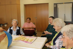 Fünf Seniorinnen sitzen um einen Tisch mit frischem Teig.