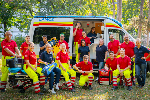 Gruppenfoto vom Schulungsteam vor einem Rettungsfahrzeug