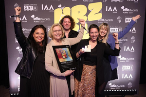 Gruppenfoto fünf Personen stehen freudig vor Fotowand bei den Effie Awards, halten Awards in der Hand und lächeln in Kamera