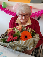 Eine ältere Frau mit Brille hält einen großen Blumenstrauß.