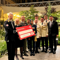 Gruppenbild mehrere Personen vom Samariterbund Wien in Abenduniform in Arkadenhof, halten Scheck in der Hand