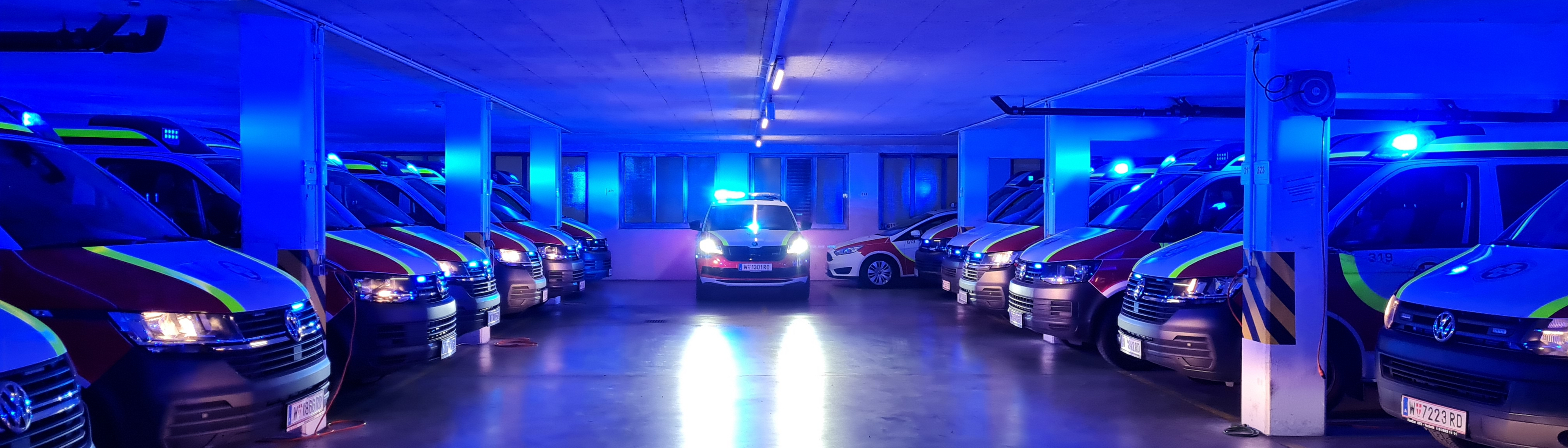 Abgedunkelte Garage mit Einsatzfahrzeugen mit Blaulicht